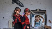 فتاتان فلسطينيتان أمام لوحة جدارية خلال معرض بعنوان "الاحتلال يقتل الطفولة"، غزة ( Getty)