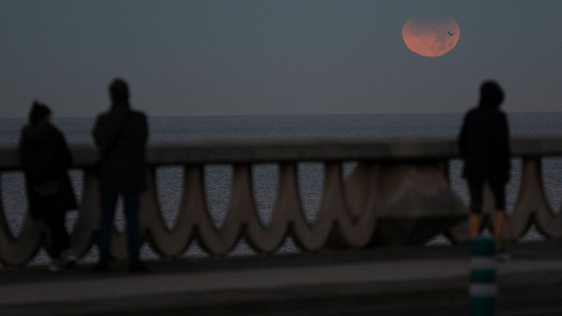 لاحظ ثلاثة أشخاص خسوفًا جزئيًا للقمر من لاكورونيا، إسبانيا (إم ديلان/ Getty)