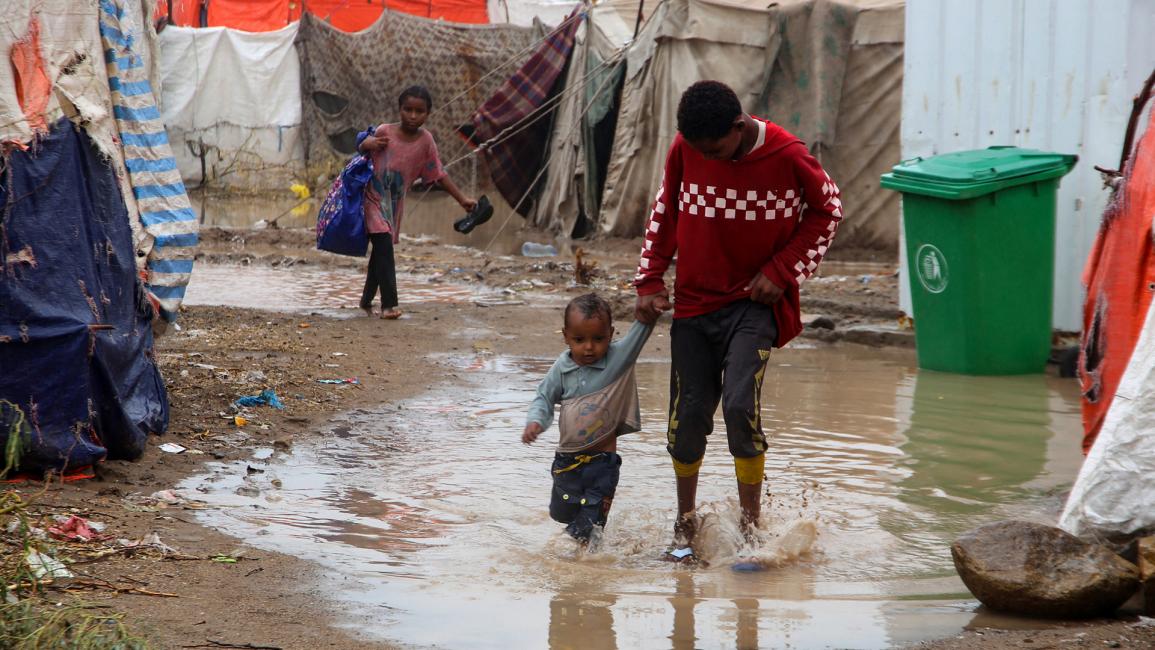 أطفال يسيرون في مياه الفيضانات خارج الخيام (خالد زياد/Getty)