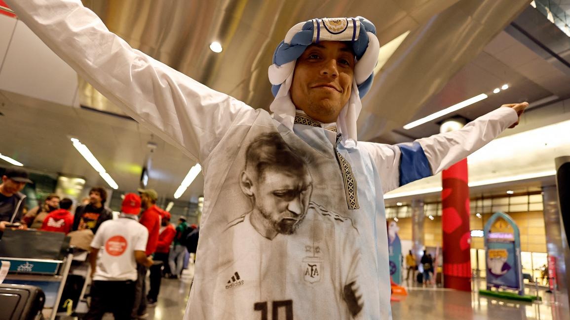 مشجع يرتدي غطاء رأس بألوان علم الأرجنتين وصورة ليونيل ميسي مطبوعة على ملابسه (حمد بن محمد/ رويترز)
