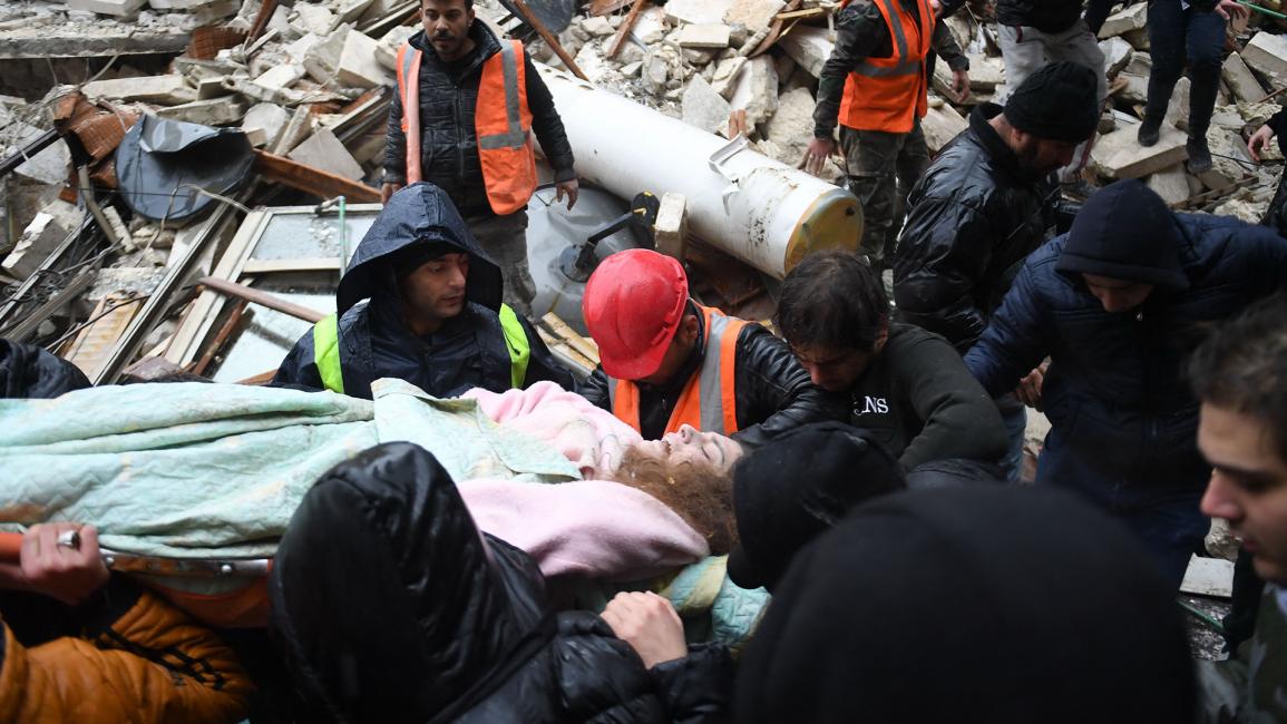الدفاع المدني السوري ينقل امرأة مصابة بعد إنقاذها من أنقاض مبنى منهار في مدينة حلب (Getty)