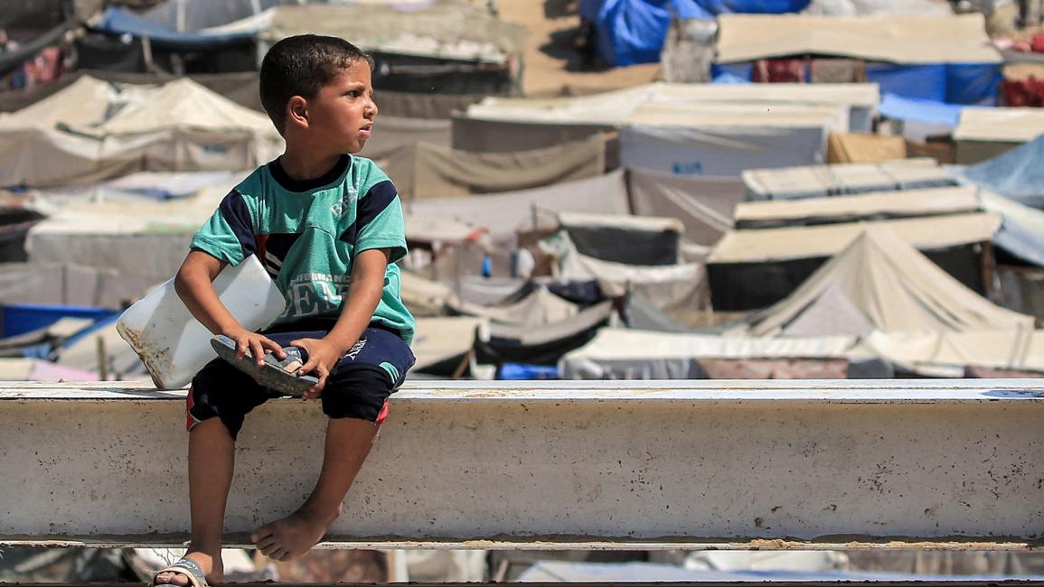 طفل يجلس بالقرب من مخيمات النازحين ليستريح بعد معاناة البحث عن مياه الشرب (إياد بابا/ Getty)