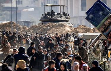 فلسطينيون ينزحون من خانيونس على مقربة من دبابة إسرائيلية، 30 يناير 2024 (Getty)