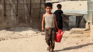 طفل يحمل إبريق ماء في مخيم بالقرب من قرية قاح شمال غرب إدلب في 28 أكتوبر 2020 (أحمد الأطرش/فرانس برس)