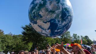نشطاء مناخ في لاهاي يمدون يدهم إلى مجسم الأرض ضد دعم الحكومة لصناعة الوقود الأحفوري، في 9 سبتمبر 2023 (Getty)