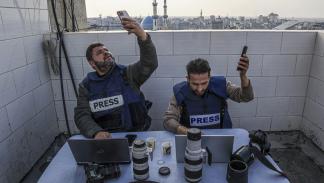 صحافيان يحاولان الاتصال بشبكة الإنترنت في رفح، 27 ديسمبر 2023 (سعيد الخطيب/ فرانس برس)