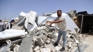 فلسطيني فوق أنقاض منازل هدمها الاحتلال في قرية بيرين بالخليل، 04 يوليو 2024 (الأناضول)