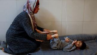 أم تساعد إبنها الذي يعاني من سوء التغذية، غزة 8 يوليو 2024 (رويترز)