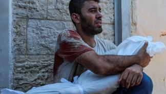 أب فلسطيني يحمل جثة ابنه في وسط قطاع غزة / 9 يوليو 2024 (رويترز)