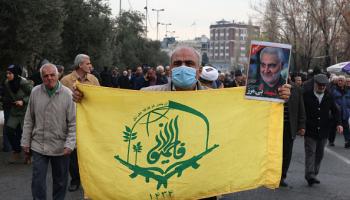 مواطن إيراني يرفع علم مليشيا فاطميون، طهران 12 يناير 2024 (فرانس برس)