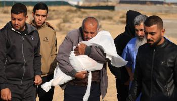 فلسطينيون يحملون جثة طفل وسط الحرب على غزة (محمود الهمص/ فرانس برس) 