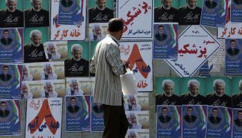 إيراني يمر أمام ملصقات انتخابية في طهران أمس (فاطمة بهرامي/الأناضول)