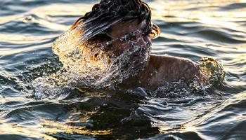 شاب عراقي يسبح في نهر شط العرب لتخفيف الحر، يونيو 2024 (فرانس برس)