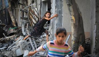 طفلتان تتسلقان فوق أنقاض منازل دمرها الاحتلال في النصيرات، 9 يونيو 2024 (Getty)