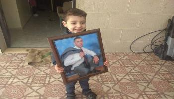 نجل الشهيد الفلسطيني صالح البرغوثي يحمل صورة والده(تويتر)