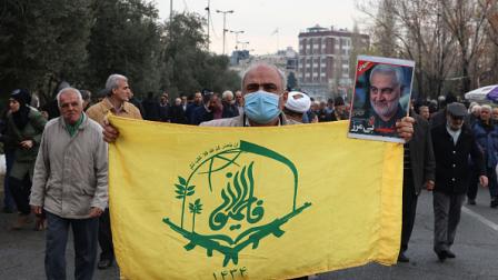 مواطن إيراني يرفع علم مليشيا فاطميون، طهران 12 يناير 2024 (فرانس برس)