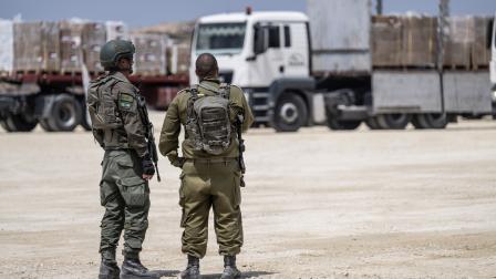 جنديان إسرائيليان قرب شاحنات مساعدات، الأول من مايو الماضي (جاك غويز/فرانس برس)