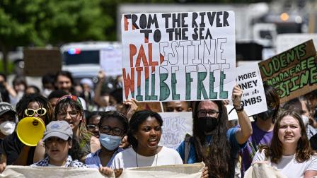 طالب أميركي يرفع لافتة "من النهر إلى البحر فلسطين ستكون حرة" (سيلال جونز/الأناضول)