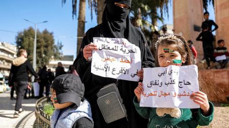 زوجة معتقل سوري رفقة أطفالها بوقفة ضد التعذيب بإدلب، مارس2024(Getty)