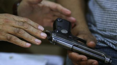 ضابط عراقي يسجل سلاحا من مواطن بمنزله في بغداد، مايو 2024(فرانس برس)