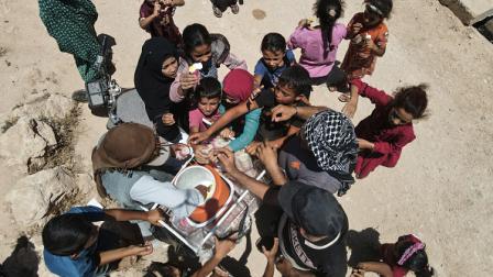 أطفال يتجمعون عند بائع متجول في مخيم للنازحين، يونيو2024 (فرانس برس)